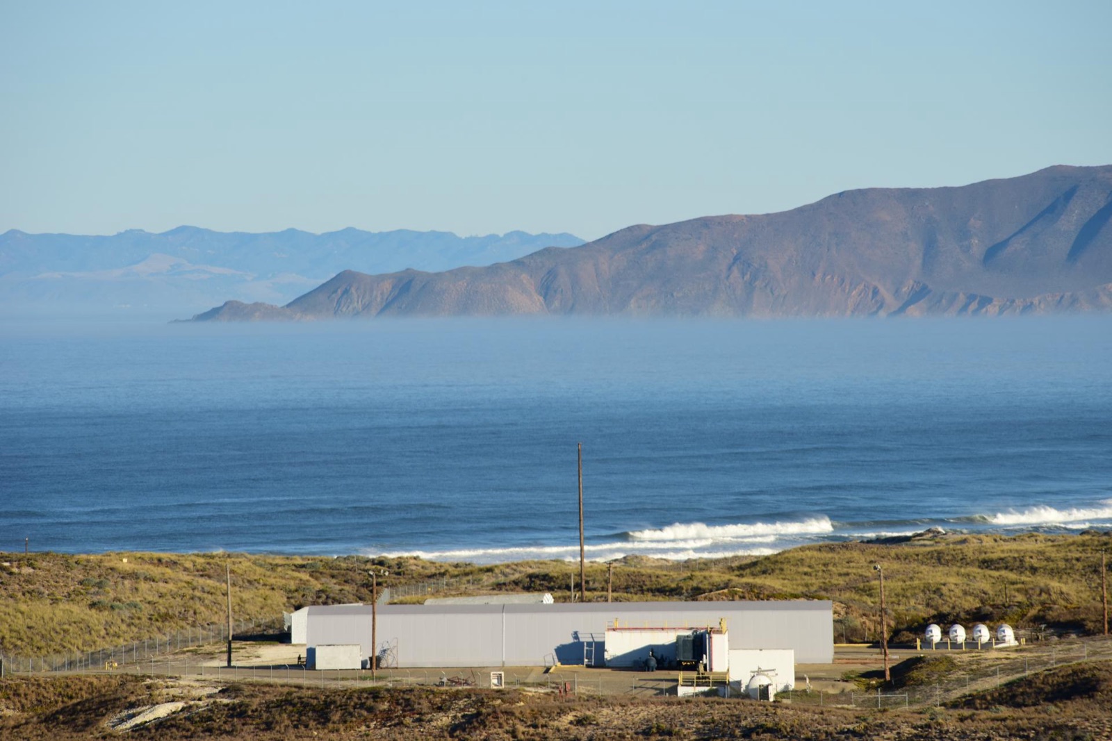 The Pacific coastline at Vandenberg with surf, bluff, and distant coastal headlands receding into haze