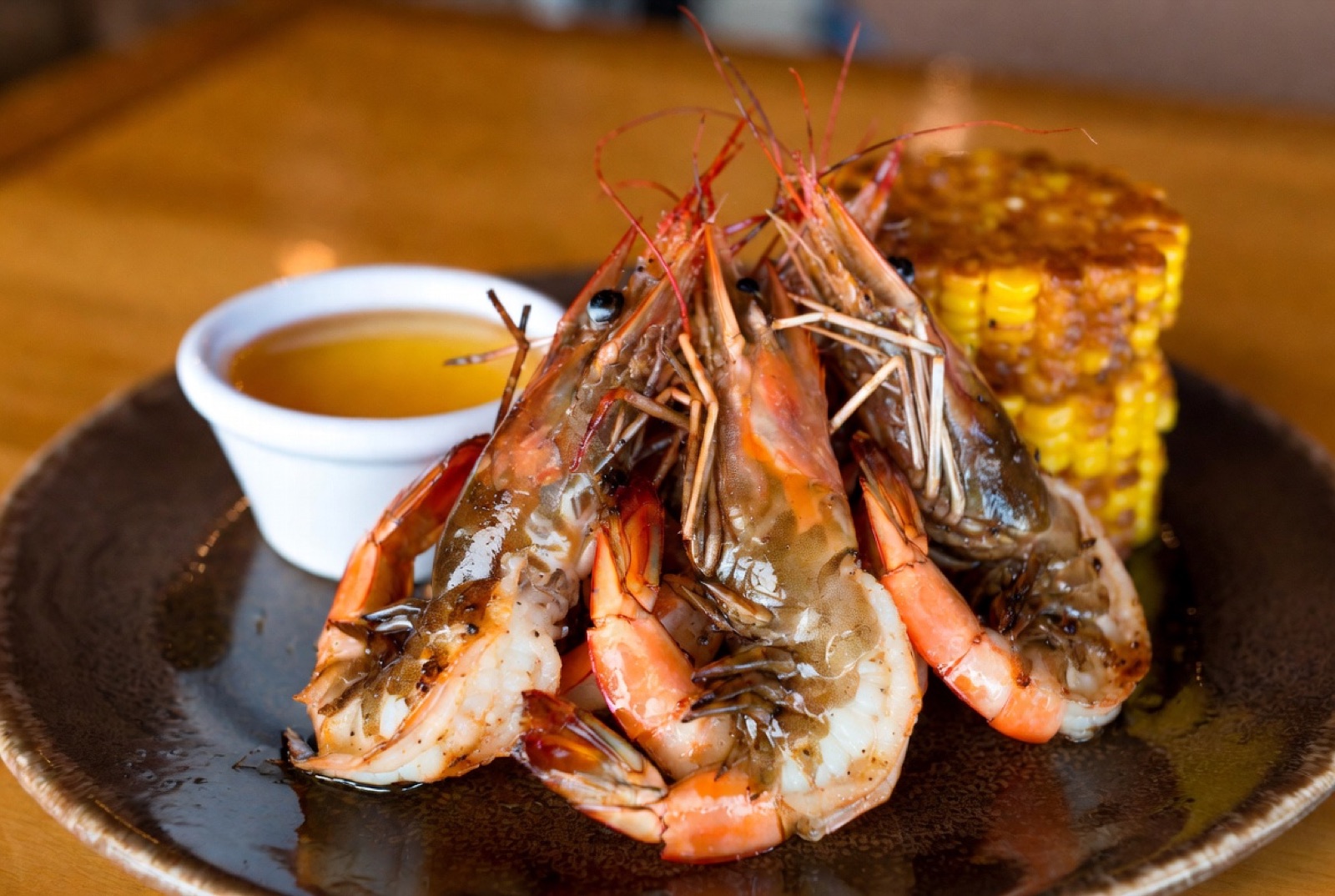 A plate of split-grilled rock shrimp at Dixie Crossroads with drawn butter and grilled corn on the side